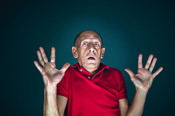 Image showing Close up portrait of crazy scared and shocked man isolated on dark background