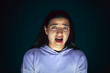 Image showing Close up portrait of young crazy scared and shocked woman isolated on dark background