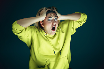Image showing Close up portrait of young crazy scared and shocked woman isolated on dark background