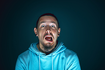 Image showing Close up portrait of young crazy scared and shocked man isolated on dark background