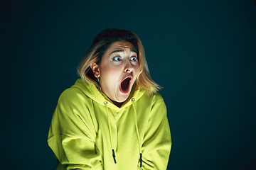 Image showing Close up portrait of young crazy scared and shocked woman isolated on dark background