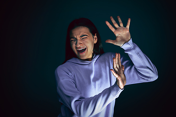 Image showing Close up portrait of young crazy scared and shocked woman isolated on dark background