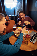 Image showing Excited fans with mobile app for betting and score on their devices. Gambling, emotions