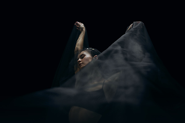 Image showing Graceful classic female ballet dancer isolated on black studio background. The grace, artist, movement, action and motion concept.