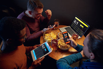 Image showing Excited fans with mobile app for betting and score on their devices. Gambling, emotions