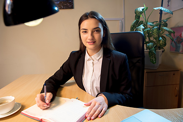 Image showing Young woman talking, working during videoconference with colleagues at home