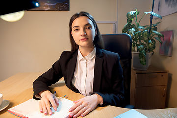 Image showing Young woman talking, working during videoconference with colleagues at home