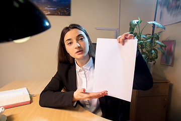 Image showing Young woman talking, working during videoconference with colleagues at home