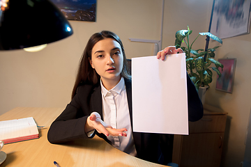 Image showing Young woman talking, working during videoconference with colleagues at home