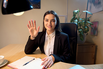 Image showing Young woman talking, working during videoconference with colleagues at home