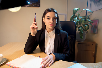 Image showing Young woman talking, working during videoconference with colleagues at home