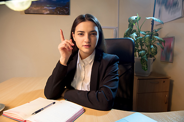 Image showing Young woman talking, working during videoconference with colleagues at home