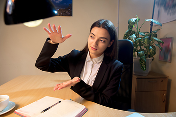 Image showing Young woman talking, working during videoconference with colleagues at home