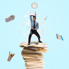 Image showing Office worker, businessman, sportsman fighting with deadlines standing on the bunch of documents