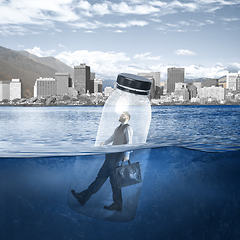 Image showing Office worker, businessman closed in bottle heading to work on the river with megapolis on the background