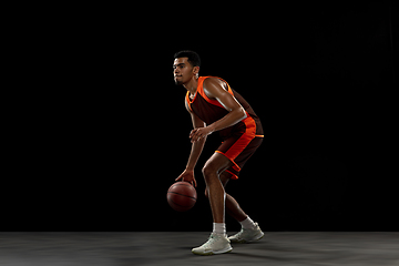 Image showing Young african basketball player training on black studio background.