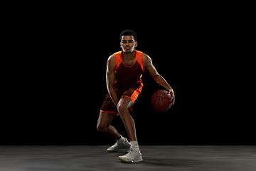 Image showing Young african basketball player training on black studio background.