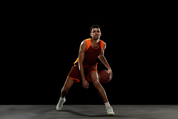 Image showing Young african basketball player training on black studio background.