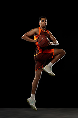 Image showing Young african basketball player training on black studio background.