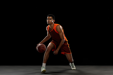 Image showing Young african basketball player training on black studio background.