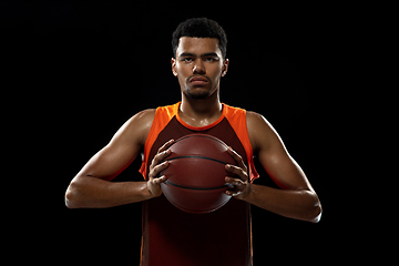 Image showing Young african basketball player training on black studio background.