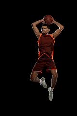 Image showing Young african basketball player training on black studio background.