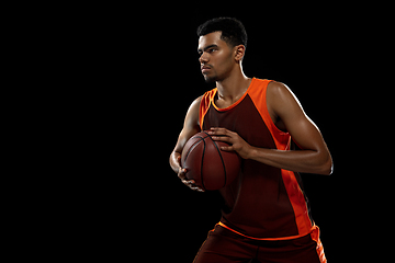 Image showing Young african basketball player training on black studio background.