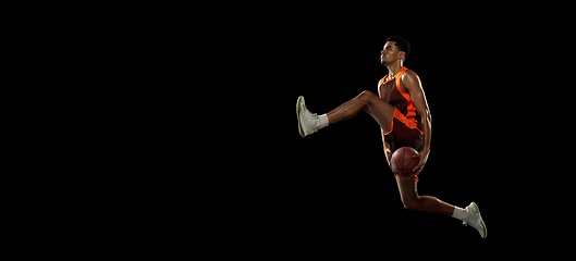 Image showing Young african basketball player training on black studio background.