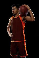 Image showing Young african basketball player training on black studio background.