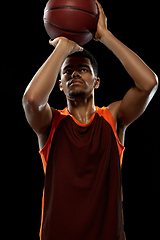 Image showing Young african basketball player training on black studio background.