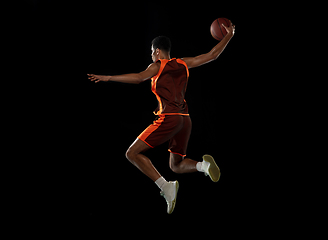 Image showing Young african basketball player training on black studio background.