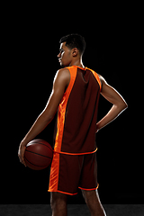 Image showing Young african basketball player training on black studio background.