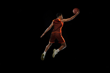 Image showing Young african basketball player training on black studio background.