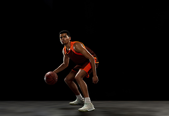 Image showing Young african basketball player training on black studio background.