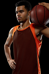 Image showing Young african basketball player training on black studio background.