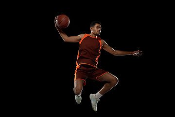 Image showing Young african basketball player training on black studio background.