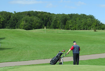 Image showing Senior  holding a golf caddie