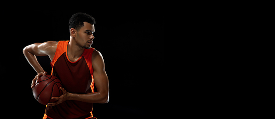 Image showing Young african basketball player training on black studio background.