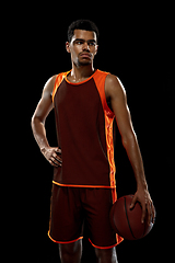 Image showing Young african basketball player training on black studio background.