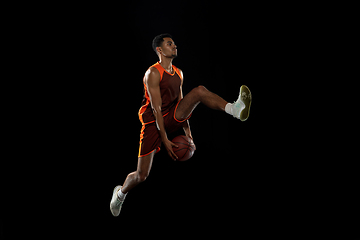 Image showing Young african basketball player training on black studio background.