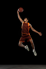 Image showing Young african basketball player training on black studio background.