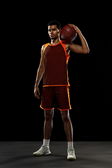 Image showing Young african basketball player training on black studio background.