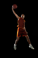 Image showing Young african basketball player training on black studio background.