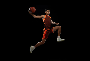 Image showing Young african basketball player training on black studio background.