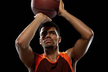 Image showing Young african basketball player training on black studio background.