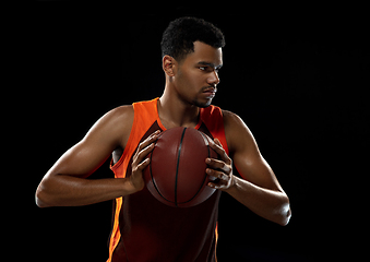 Image showing Young african basketball player training on black studio background.