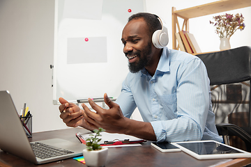 Image showing Online english courses at home. Smiling man teaches students remotely in interior of living room