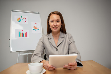 Image showing Young woman talking, working during videoconference with colleagues at home office