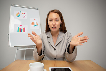 Image showing Young woman talking, working during videoconference with colleagues at home office