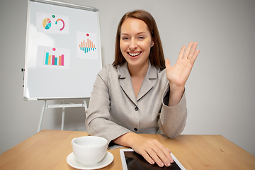 Image showing Young woman talking, working during videoconference with colleagues at home office